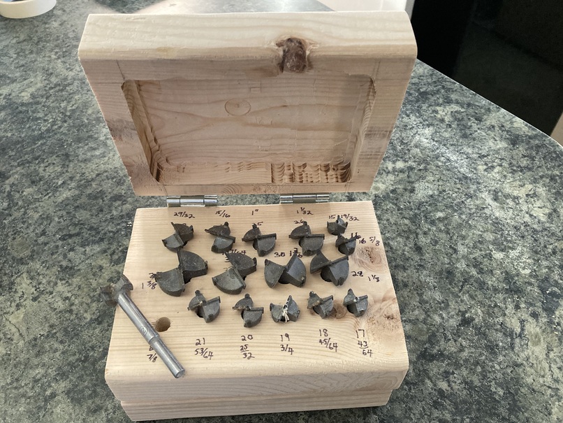 the top 2x6 flips up, revealing forstner bits